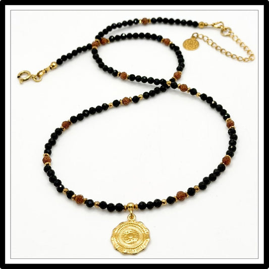 Naszyjnik z czarnym turmalinem i piaskiem pustyni z okrągłą złotą zawieszką na białym tle