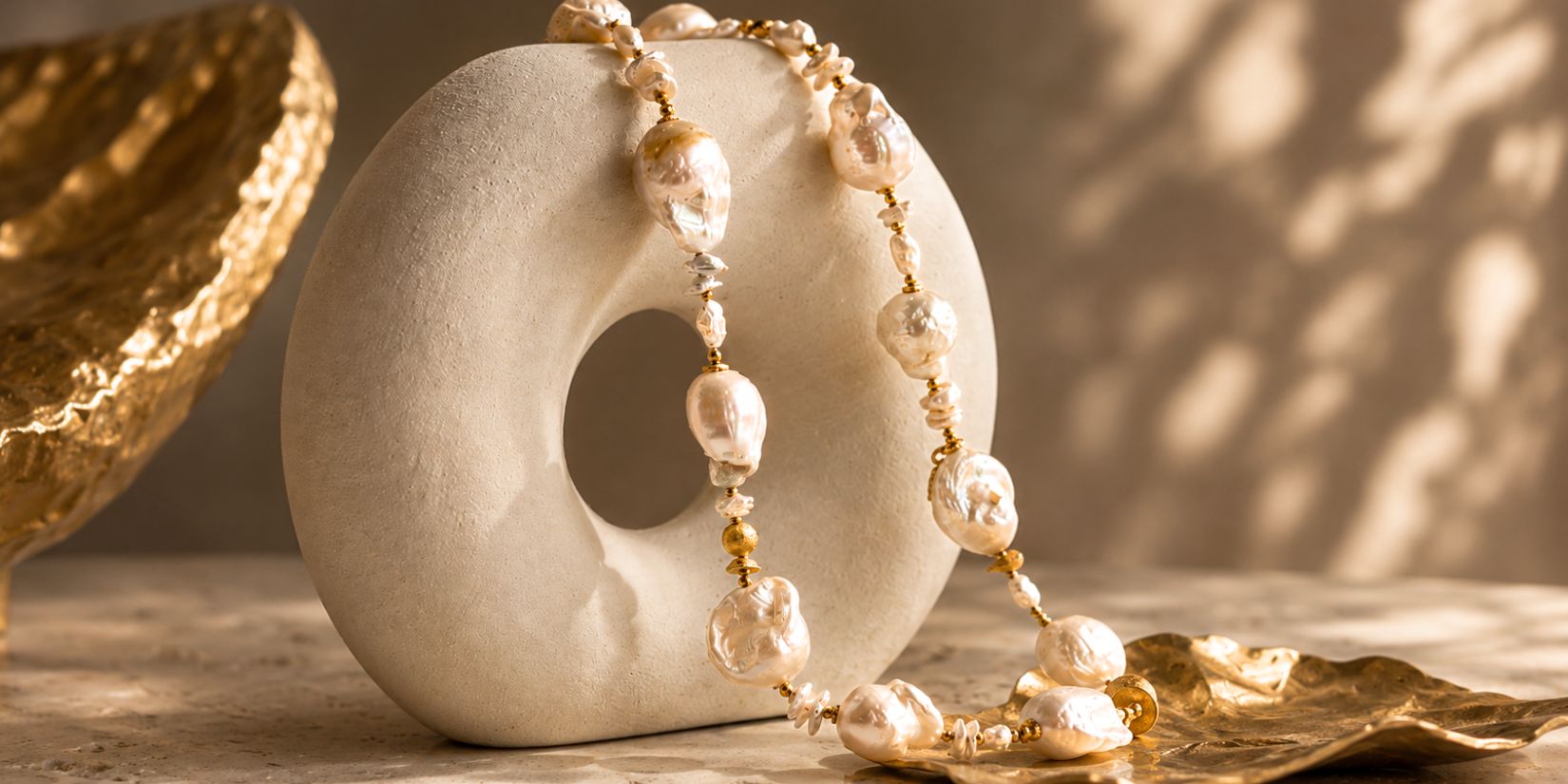 Perły barokowe w biżuterii Meritano Jewellery na jasnej, organicznej formie ekspozycyjnej w ciepłym świetle 