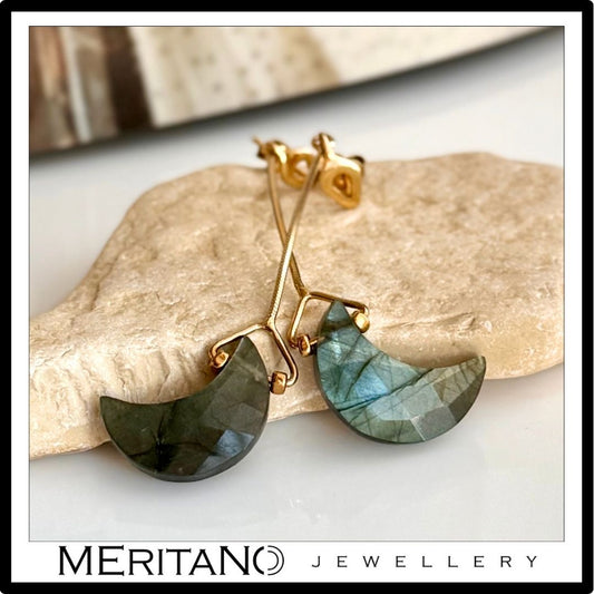 Wiszące kolczyki z księżycem z labradorytu, leżące na kamieniu Wiszące kolczyki z księżycem z labradorytu, leżące na kamieniu