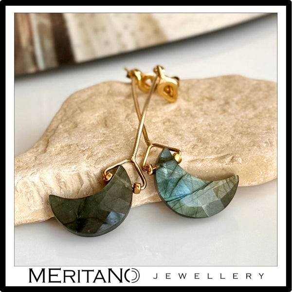 Wiszące kolczyki z księżycem z labradorytu, leżące na kamieniu