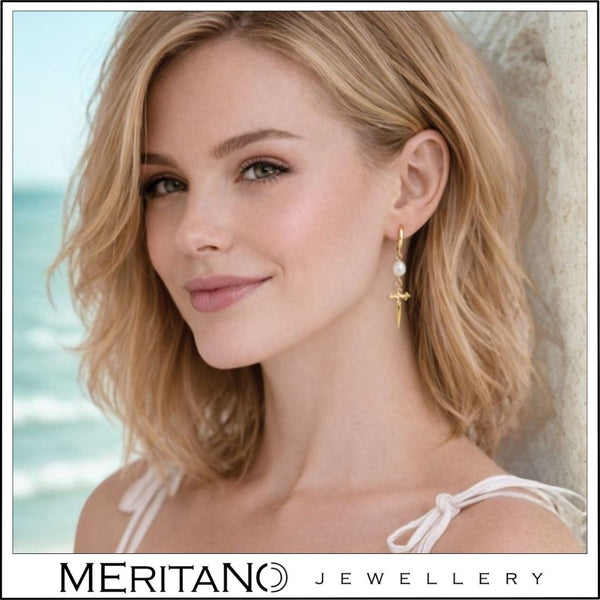 Wiszące, złote kolczyki z białą perłą i sztyletem na uchu