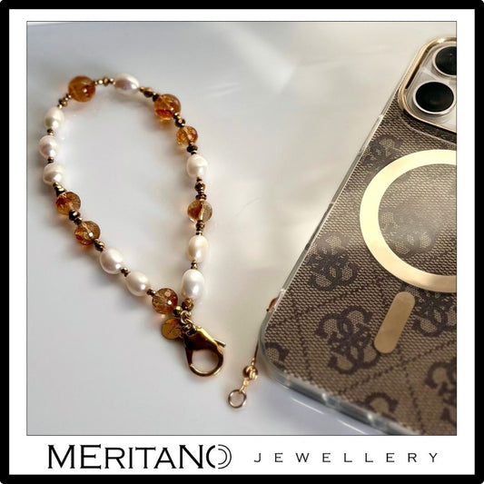 Bransoletka do smartfona z cytrynem i perłami, leżąca obok telefonu