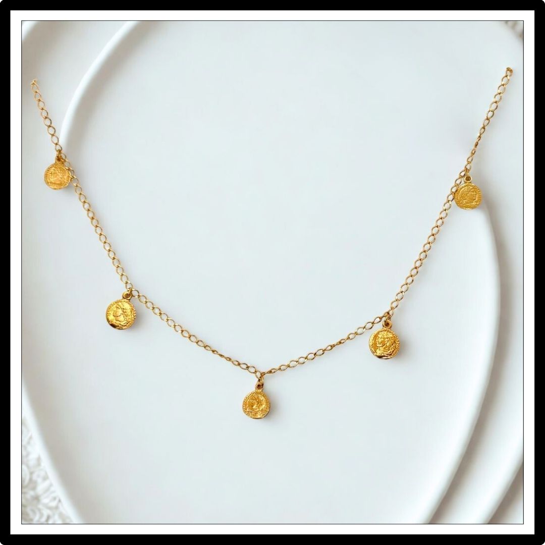Złoty łańcuszek z monetami - widok z przodu na białym tle