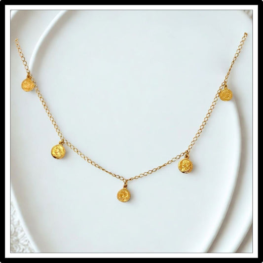 Złoty łańcuszek z monetami - widok z przodu na białym tle